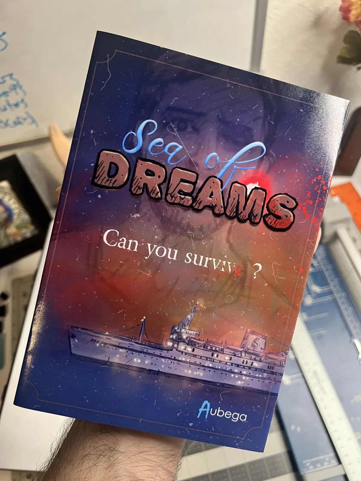 A single printed Sea of Dreams cover held up at the workbench.